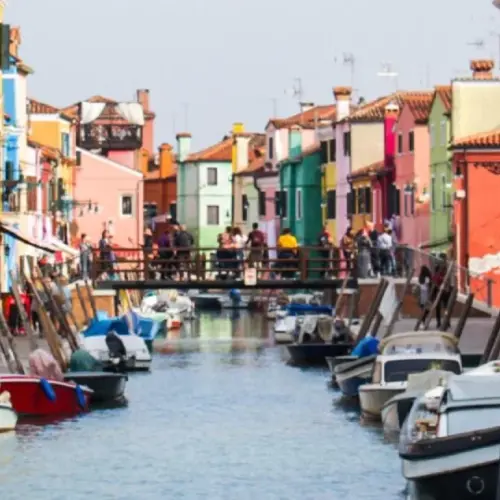 Colorful Italian city with boats for rides lined up on the rise of the river.