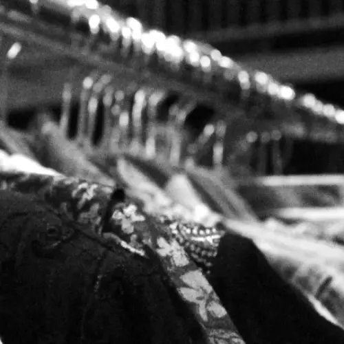 Black and white picture of clothes hanging on a rack.