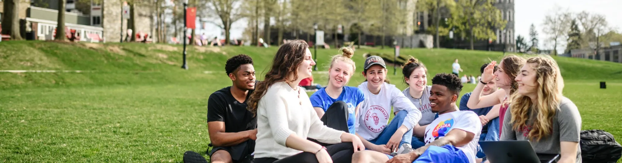 Nine students hang out on Arcadia's campus lawn