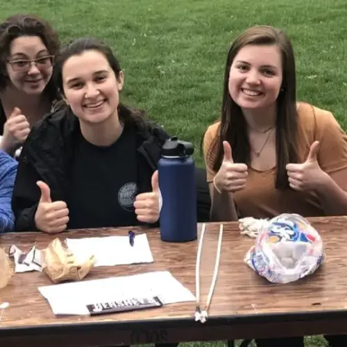 A group of women sitting together giving thumbs up
