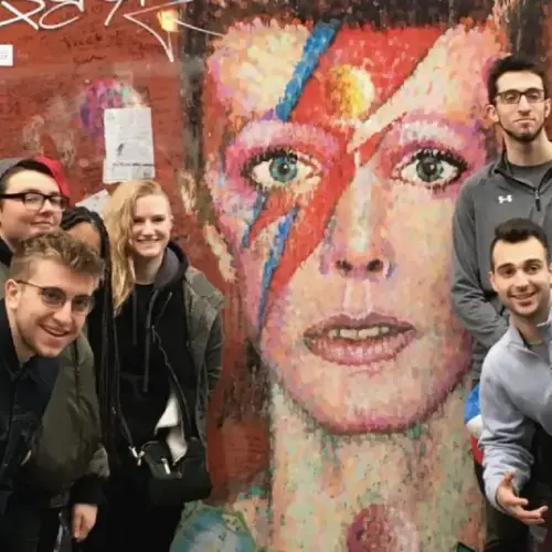 A group of students posting in front of a mural