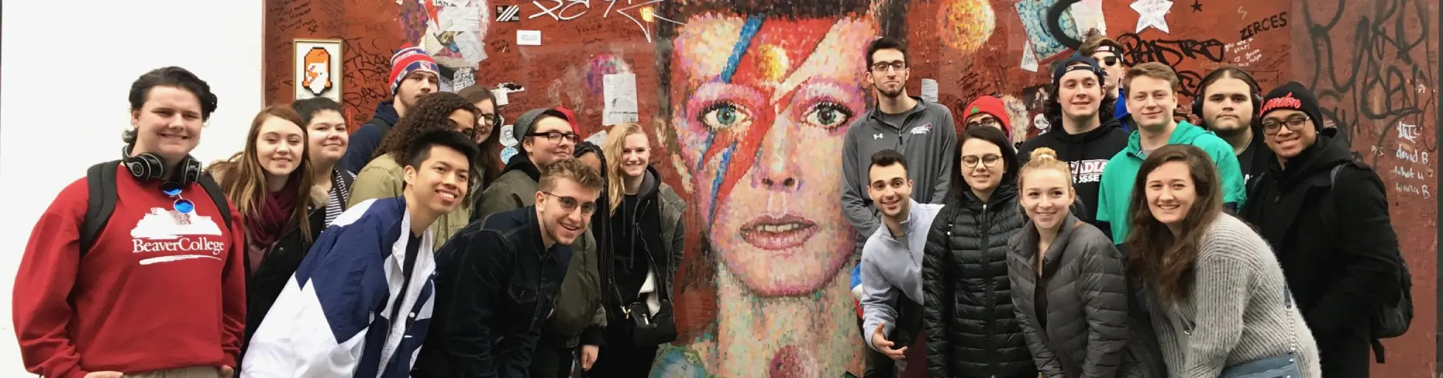 A group of students posting in front of a mural