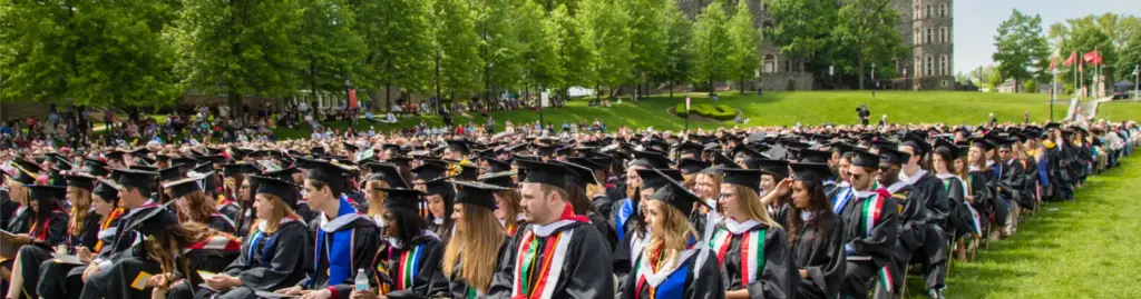 Graduation class seated in caps and gowns outside on Arcadia University's campus