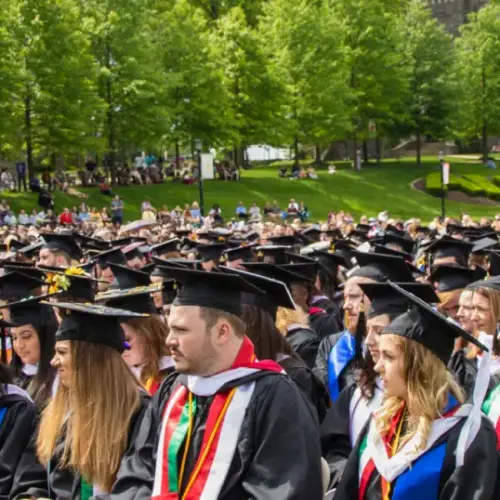 Graduation class seated in caps and gowns outside on Arcadia University's campus