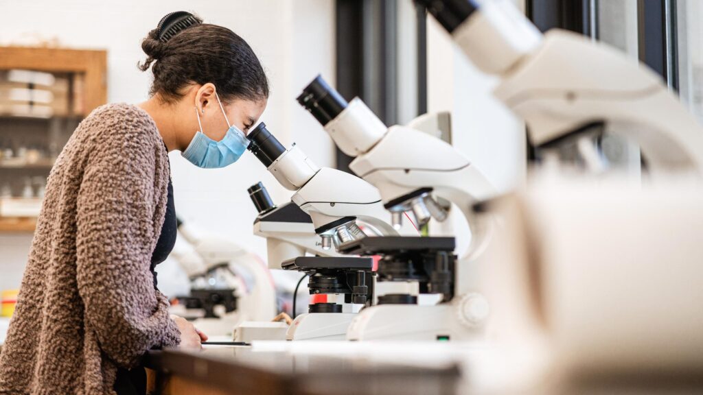 A biology student uses a microscope in a laboratory.