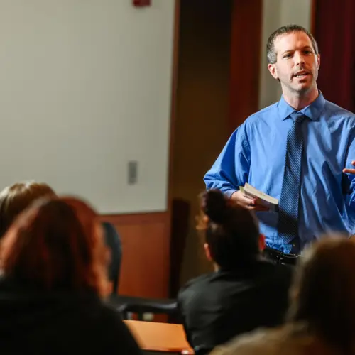 An English professor presents a lecture to a classroom full of students.