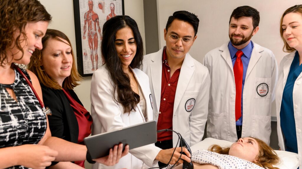 Physician assistant students gather around a patient in a lab exam.