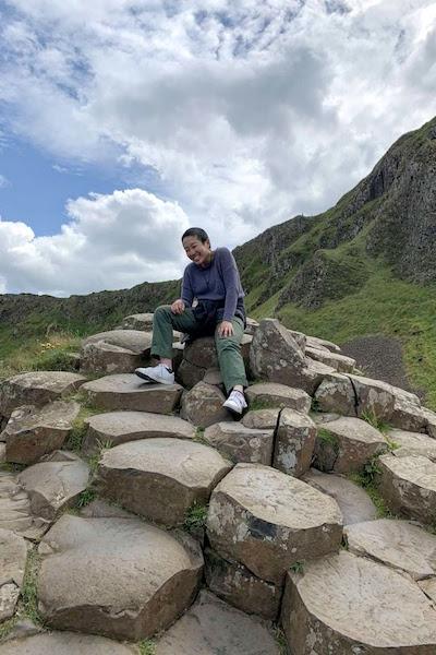 Student traveling abroad sitting on rocks in Ireland