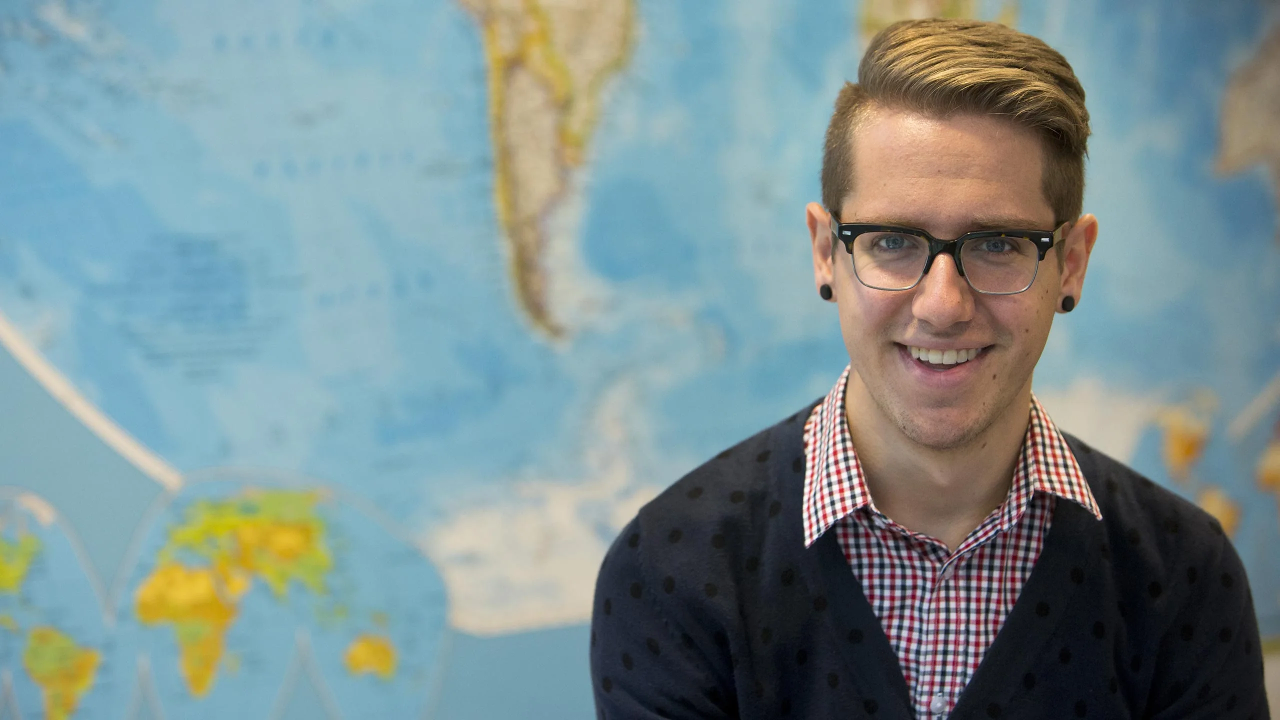 A student in a classroom in front of a map.