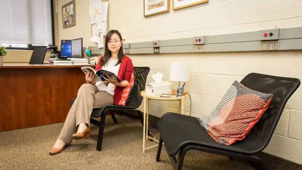 Dr. Cathy Lee in her office reading a book while sitting in a chair.