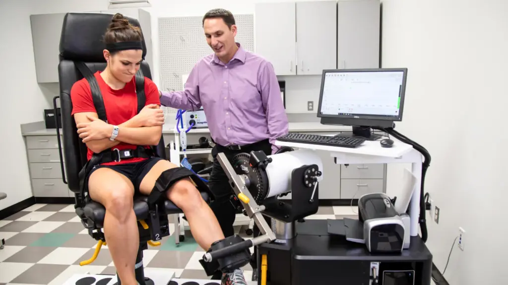 A student exercises her leg in a physical therapy lab.