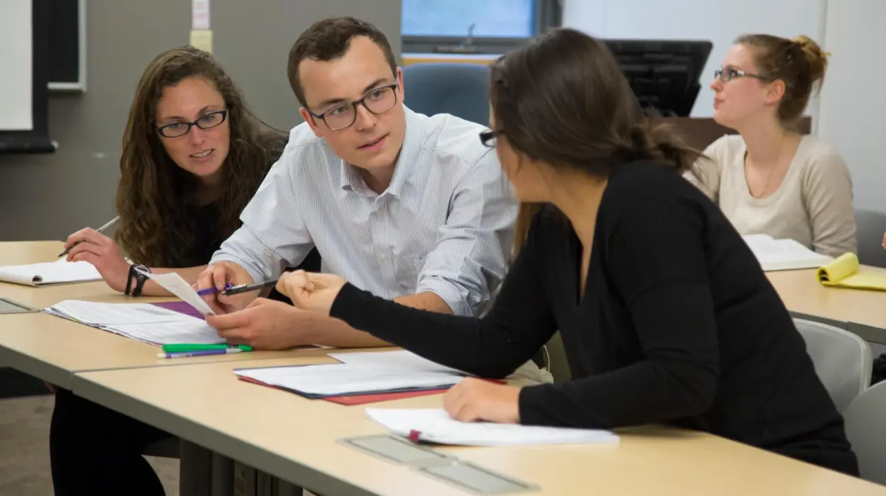 Three students discuss an assignment in a classroom.