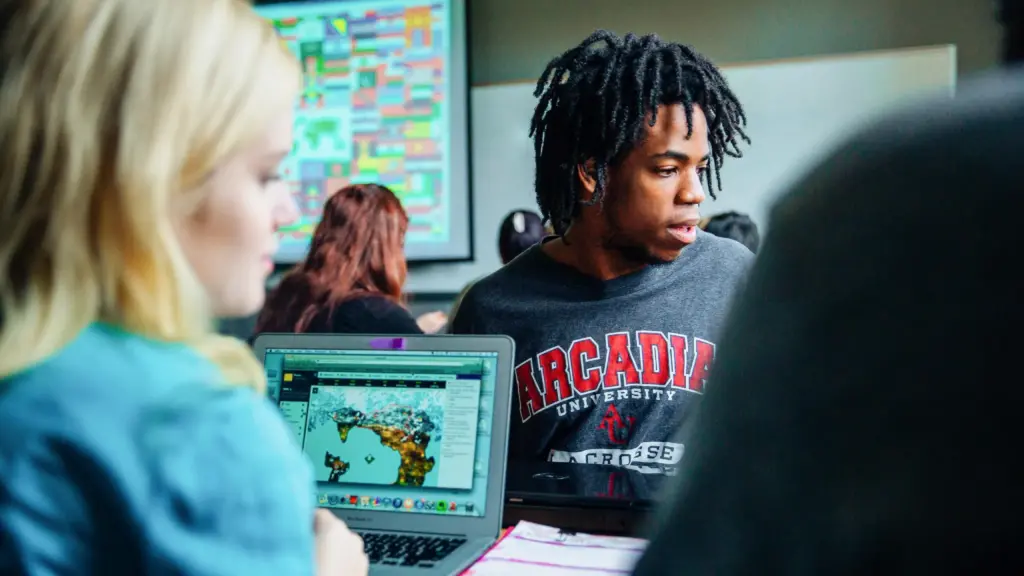 Students work on a group project with flags of the world projected in the background.