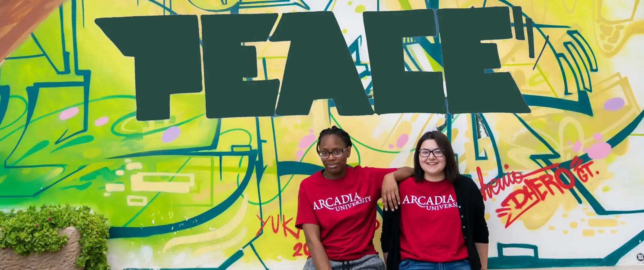 Two students sit by a peace sign.