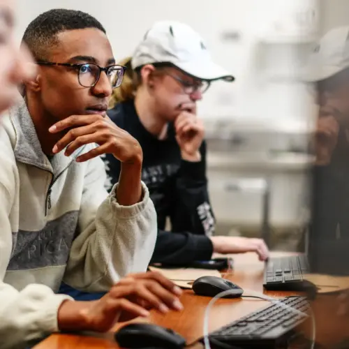 Students use computers in a classroom.