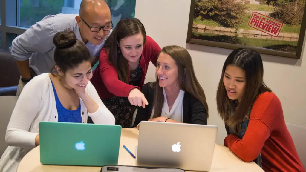 Students smile and look at laptop screens.