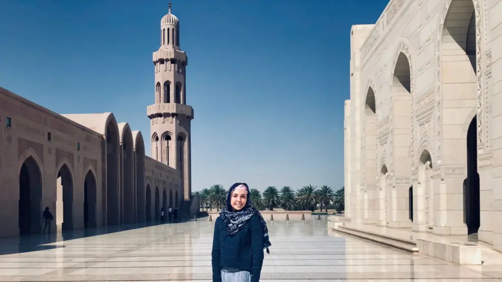 A student stands in front of a mosque in Oman.