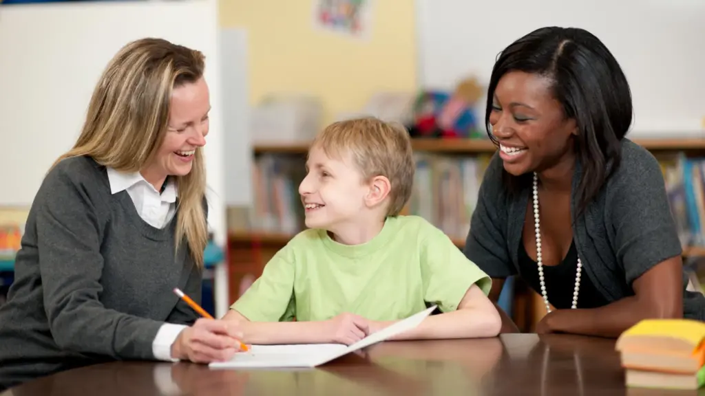 Teachers help a young student in a library.