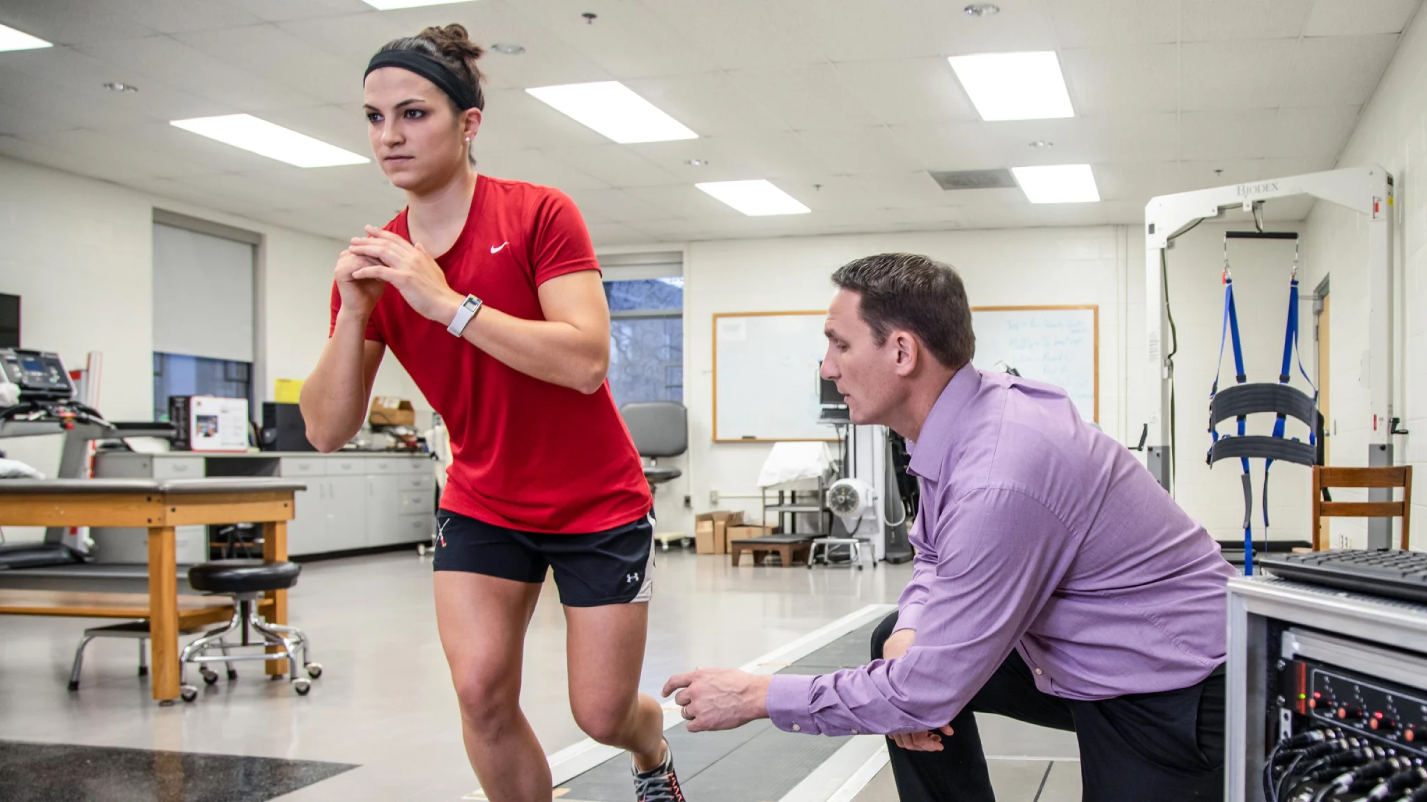 Professor helps student with physical therapy exercise.