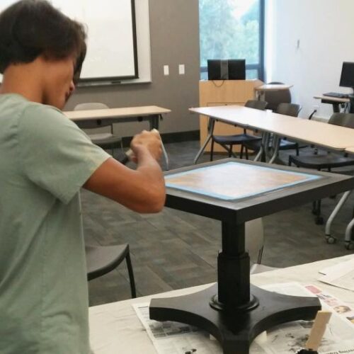 Student refurbishing a stool for the auction.
