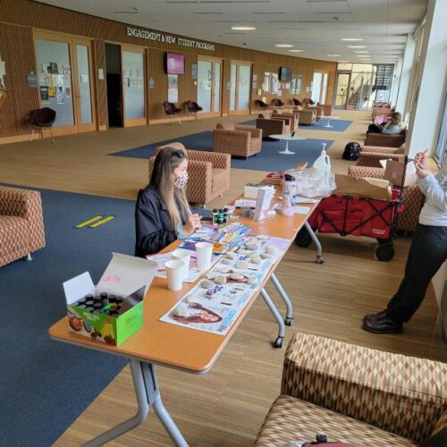 Masked students sit at a table at a wellness fair