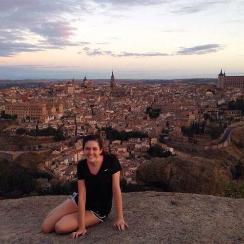 A student studying abroad sitting on a hill over a city