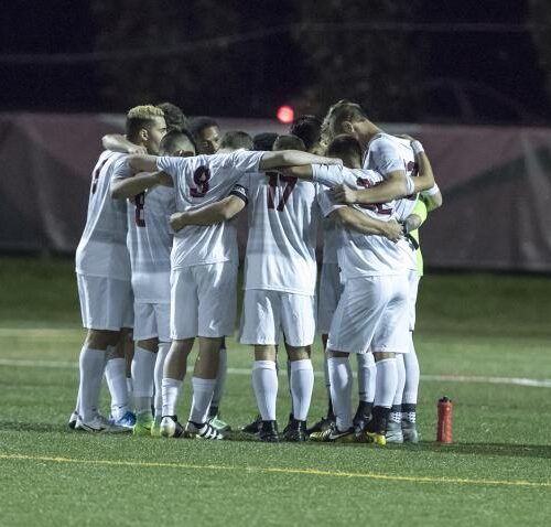 Soccer players huddled on field.