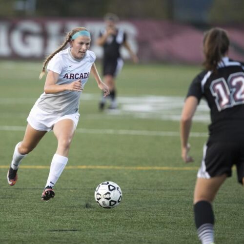 A women's soccer player chases after the ball