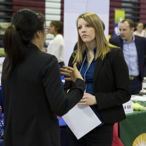A student listens to a recruiter at the spring internship fair