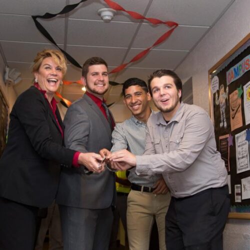 Four people holding scissors to cut a ribbon for the renovated commuter lounge