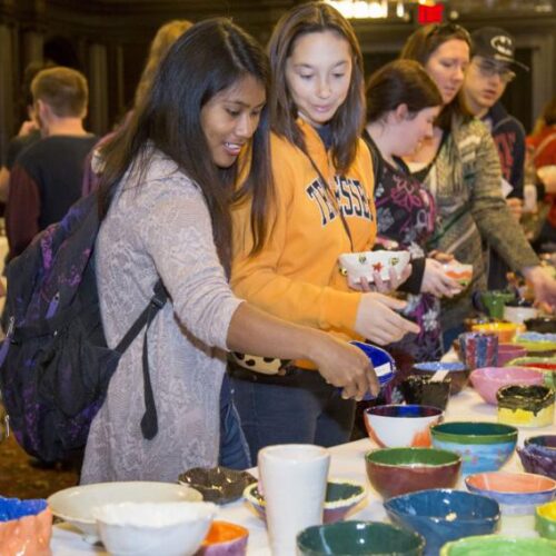 Students looking at ceramic bowls during the 25th annual empty bowl.