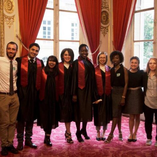 Students in graduation gowns and faculty standing together.