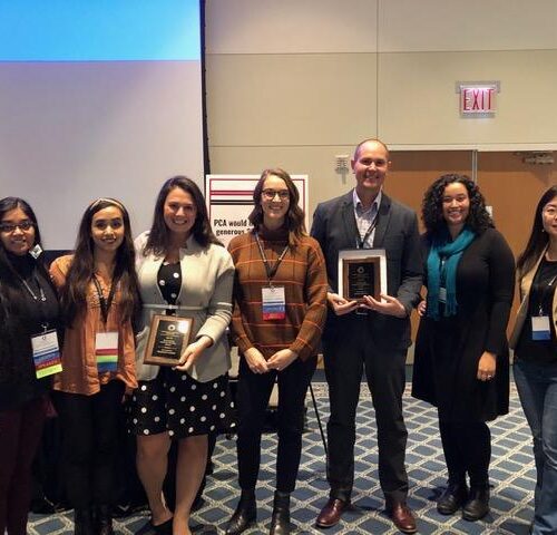 Students and faculty standing together with two holding plaques