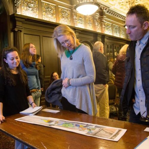 Community Members preview the Glenside Mural art on a table inside of Grey Castle