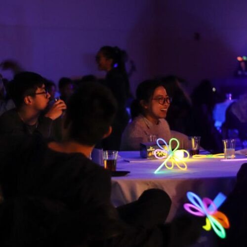 Students laughing at a table with glowing flowers.