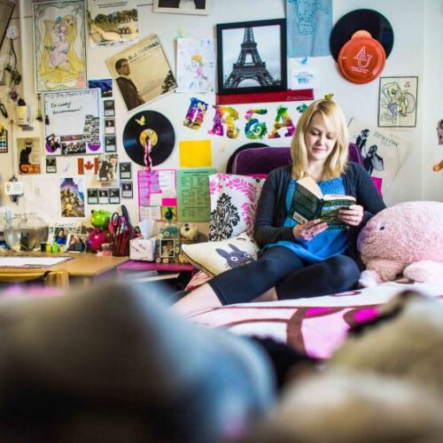 A student in their dorm bed reading a book.