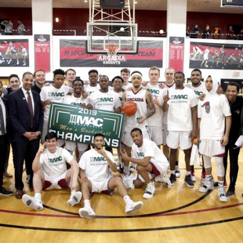 2019 Men's Basketball team gathered around MAC Champions sign in the gym.