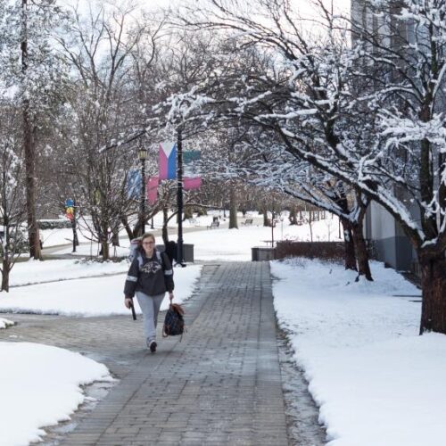 A student walks across the snowy campus.