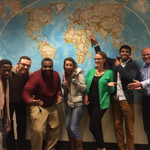 A group of people standing in front of a map of the world