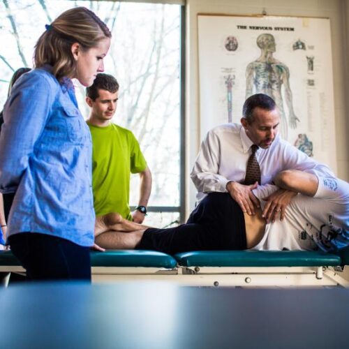 Physician assistant students gather around a patient.