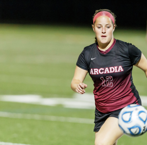 Female Arcadia soccer player runs toward the ball, blurry with speed near her