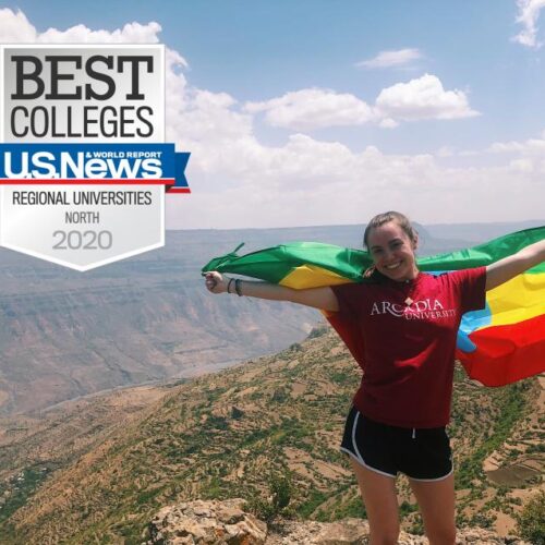 A female student holds a flag behind her at the edge of a canyon with the US News Best Colleges logo in one corner