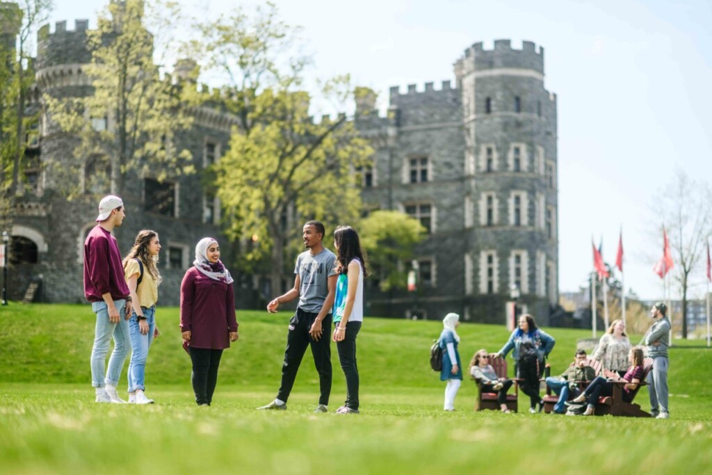 Group of students standing in grass talking in front of Greys Tower Castle