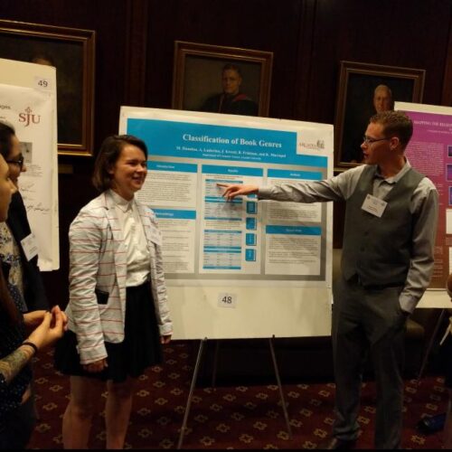 male and female students presenting poster to a group