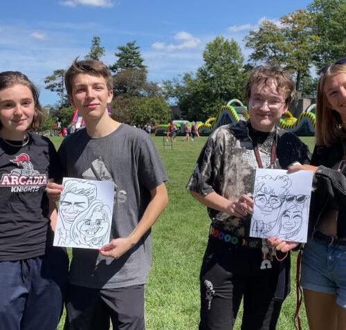 Students holding up drawings of themselves on Haber Green.