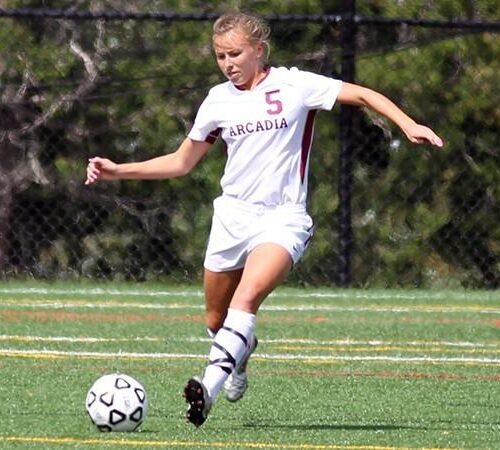 A women's soccer player kicks the ball