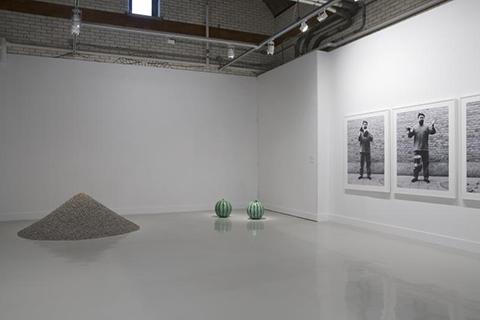 An art gallery installation with two watermelons and a big pile of an ashy substance near it