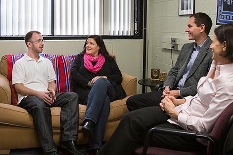 Four faculty sit together on a couch and chairs