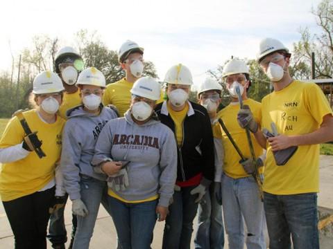 A group of people wearing hard hats with some wearing yellow shirts and two wearing Arcadia shirts
