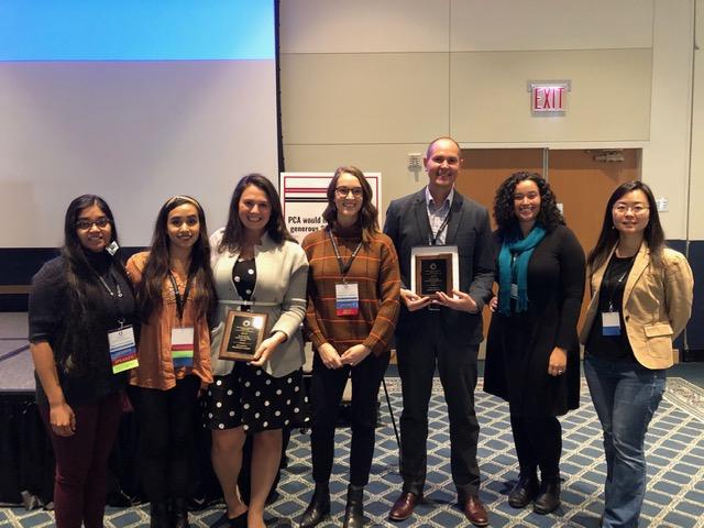 Students and faculty standing together with two holding plaques